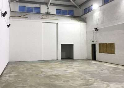 Interior of the Talocher School in Monmouth, a spacious, unfinished hall with concrete floor and white walls.