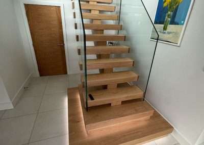 Modern oak floating staircase with glass balustrade and LED lighting