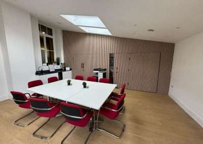 Clarence Hall: Modern meeting room with white table, red chairs, and wood paneling.