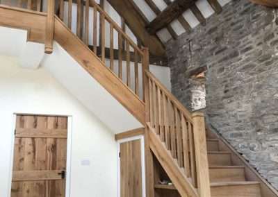 Wooden staircase and doors in a rustic building with stone walls and exposed beams