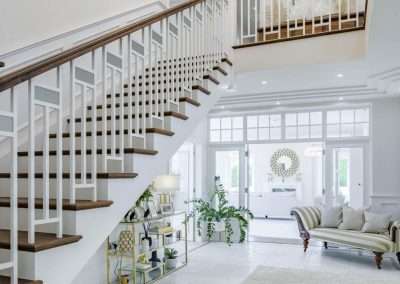 Elegant white staircase with dark wood treads in a luxurious Avarla entryway.